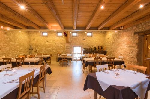 comedor con mesas y sillas y pared de piedra en Locanda Viaverde Lessinia, en Velo Veronese