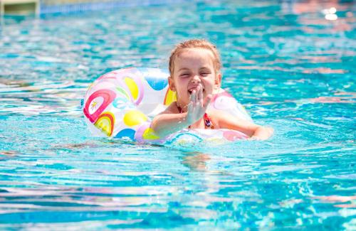 a little girl in the water in a swimming pool at Ostrov River Club in Novosëlovka