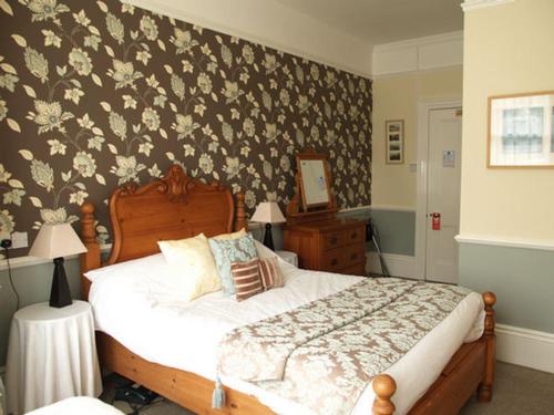 a bedroom with a bed with a floral wallpaper at Tower House 1066 in Hastings