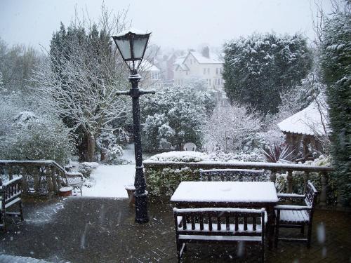 a snow covered park with benches and a street light at Tower House 1066 in Hastings