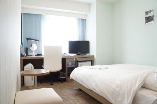 a bedroom with a bed and a desk with a tv at Daiwa Roynet Hotel Okinawa-Kenchomae in Naha