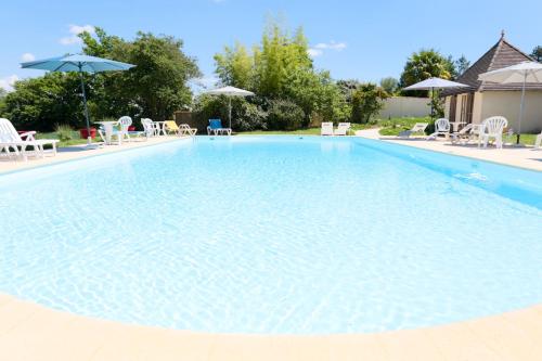 une grande piscine bleue avec chaises et parasols dans l'établissement Résidence du Château de Bégué, à Cazaubon
