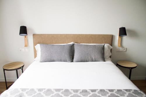 sypialnia z dużym łóżkiem z dwoma stołami w obiekcie Lux Apartamentos Rosalia w Santiago de Compostela