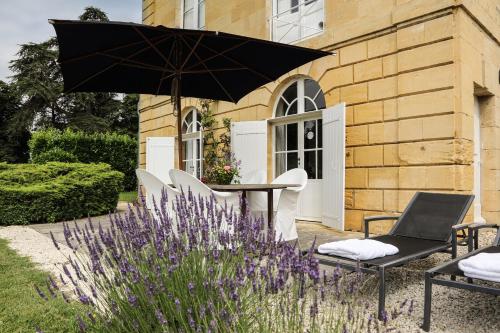 a patio with a table and chairs and an umbrella at Château Les Merles et ses Villas in Mouleydier