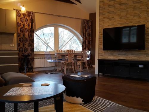 a living room with a table and a tv at City Dawn Gate Apartment in Vilnius