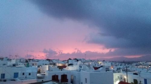 a group of white buildings with a sunset in the background at Manos Rooms in Mýkonos City