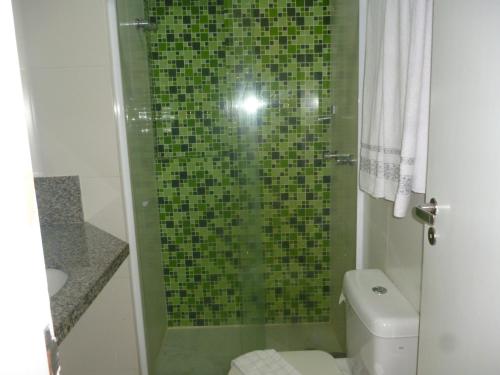 a bathroom with a green tiled shower with a toilet at Bahia Flat 117 in Salvador