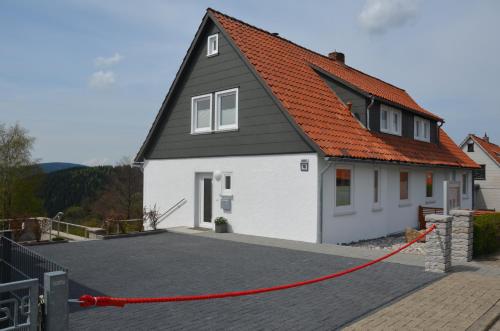 a house with a red roof on a driveway at Landhäuser Bergwiese - Ferienhaus Höhenblick in Sankt Andreasberg