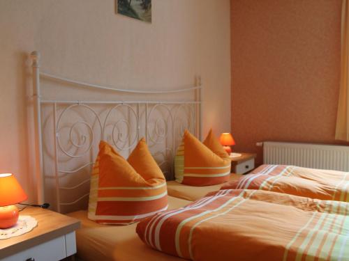 two beds in a bedroom with orange and white pillows at Bright apartment on the Baltic coast in Wiek auf Rügen