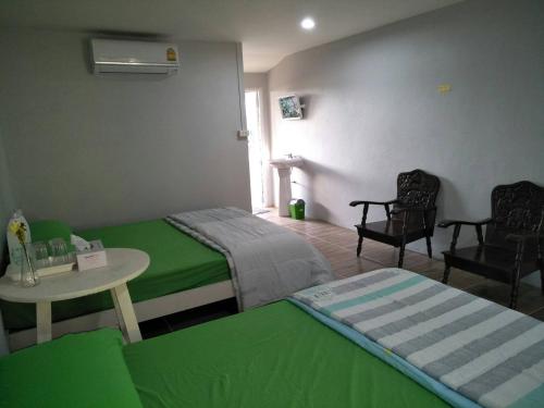 a room with two beds and a table and chairs at Oui Kaew Homestay in Phayao