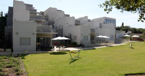 a large white building with umbrellas in a yard at Keshet Eilon - Suites and Villas in Elon