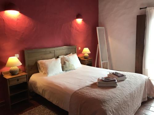 a bedroom with a large bed with red walls at Herdade Do Freixial - Turismo Rural in Vila Nova de Milfontes