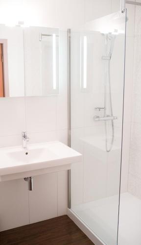 a white bathroom with a sink and a shower at The Originals City, Hôtel Le Sextant, Toulouse Sud in Labège