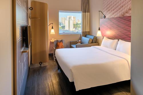 um quarto de hotel com uma grande cama branca e uma janela em ibis Sao Bernardo do Campo em São Bernardo do Campo