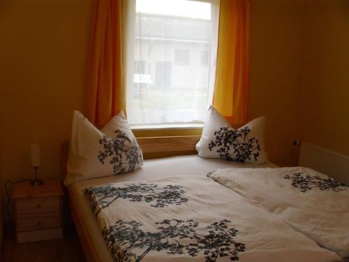 ベルガーエンデ・レートヴィッシュにあるLush Bungalow in BÃrgerende-Rethwisch with BBQのベッド(枕付)、窓(オレンジ色のカーテン付)
