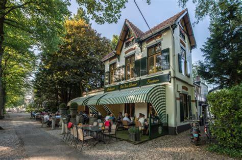 een groep mensen die buiten een gebouw zitten bij In het koetshuis in Apeldoorn