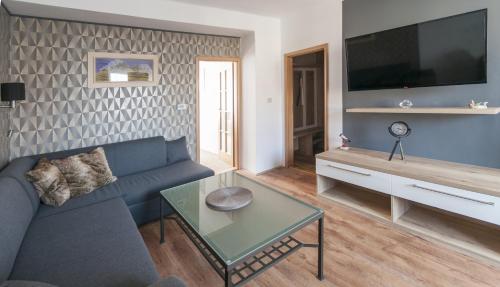 een woonkamer met een blauwe bank en een tv bij Apartman Zacler v Krkonosich in Žacléř