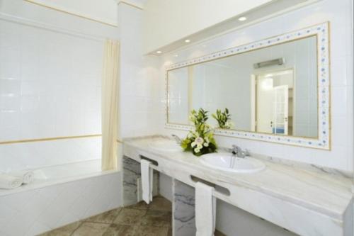 a white bathroom with a sink and a mirror at Windmill Hill in Albufeira