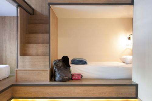 a room with a bed and a backpack sitting on a bench at Lub d Manila Makati - Central Makati, Near Nightlife in Manila