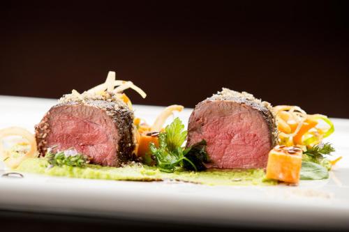two pieces of meat on a plate with vegetables at Rooms & Restaurant Ostarija in Dolenjske Toplice