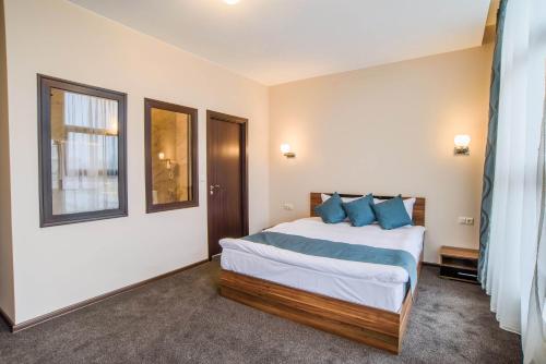 a bedroom with a large bed with blue pillows at Park-Hotel Yambol in Yambol