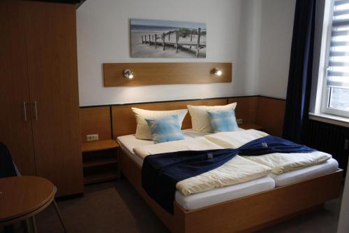 a bedroom with a large bed with blue pillows at Hotel Pellmühle in Jever