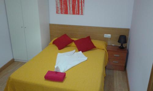 a bedroom with a yellow bed with red pillows at Caminito ARG in La Bañeza