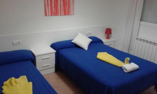 a bedroom with two beds with blue sheets and yellow pillows at Caminito ARG in La Bañeza