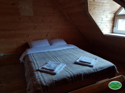 a bed in a wooden room with two towels on it at Dream Forest in Tukholʼka