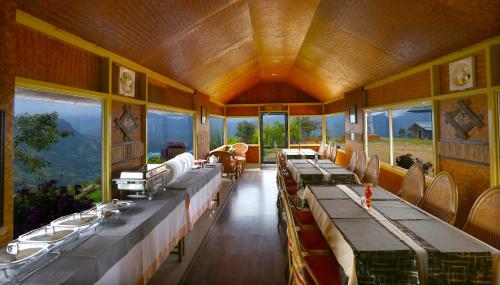 a dining room with long tables and windows at Vrindhavan Mist City Resorts in Kanthalloor