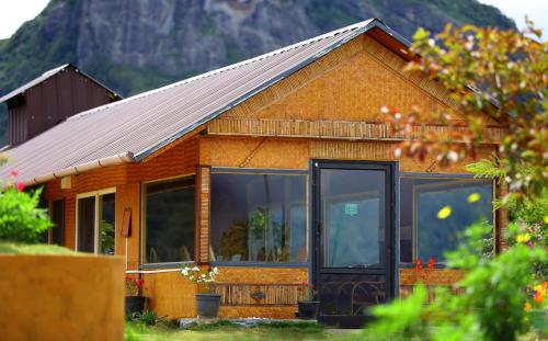 a house with glass doors and a mountain in the background at Vrindhavan Mist City Resorts in Kanthalloor