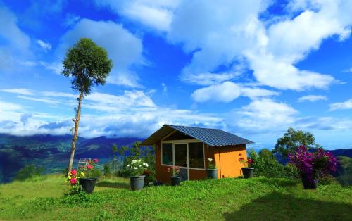 a tiny house on a hill with a tree at Vrindhavan Mist City Resorts in Kanthalloor