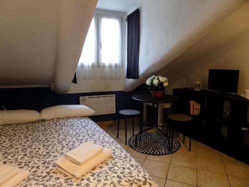 トリノにあるValentinoのベッド1台、小さなテーブル、窓が備わる客室です。