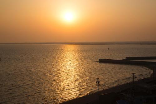 a sunset over a body of water with a pier at Ryugu Hotel in Nishio