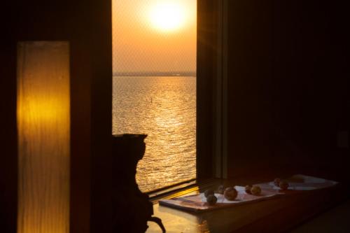 a window with a view of the ocean at sunset at Ryugu Hotel in Nishio