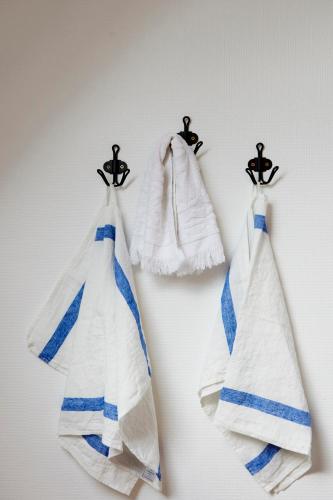 3 serviettes sont suspendues sur des crochets sur un mur dans l'établissement Manoir des petites bretonnes, à Saint-Quay-Perros