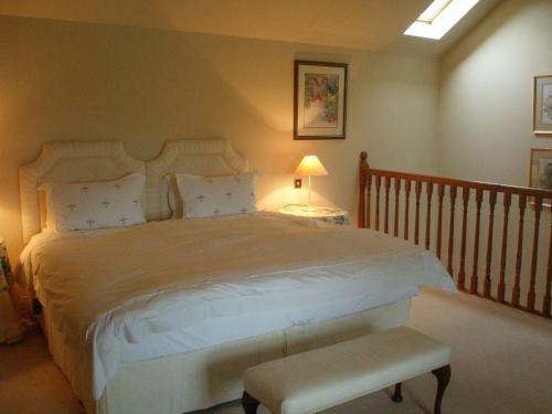 a bedroom with a large bed with a bench in it at Courtyard Cottage in Carlow
