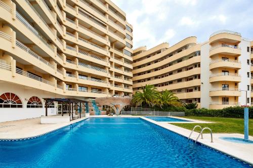 a swimming pool in front of a large building at Apartamento MarinaMar in Vilamoura
