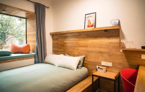 a small room with a bed and a window at Rock&Wood Cozy House in Hangzhou