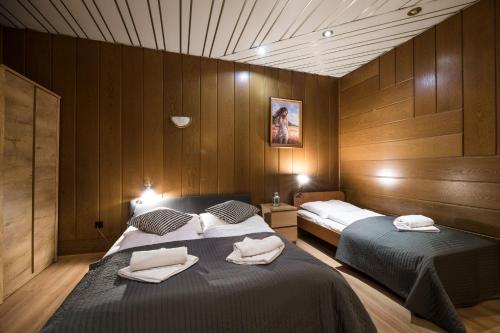 two beds in a room with wooden walls at Golden Lion Guest Rooms Szewska 19 in Kraków