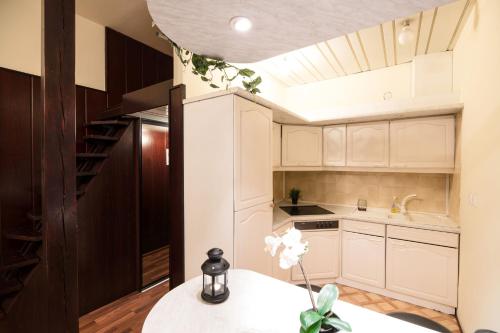 a kitchen with white cabinets and a table with flowers at Golden Lion Guest Rooms Szewska 19 in Kraków