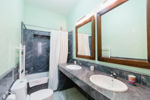 La salle de bains est pourvue de 2 lavabos, de toilettes et d'un miroir. dans l'établissement Apartamentos La Botanica, Cadiz, à Cadix