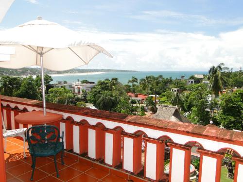 uma varanda com uma mesa e um guarda-sol e o oceano em Hotel Paraiso Escondido em Puerto Escondido