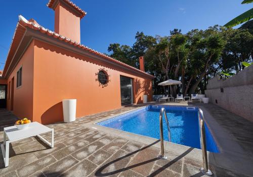 a swimming pool in front of a house at Funchal Charming Villa in Funchal