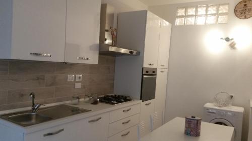 una cucina bianca con lavandino e piano cottura di Monica's Apartment a Marina di Carrara