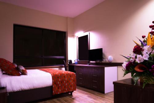 a bedroom with a bed and a desk with a television at Bidwood Suite Hotel in Nairobi