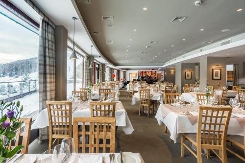 a restaurant with tables and chairs and a large window at Hotel SPA Dr Irena Eris Krynica Zdrój in Krynica Zdrój