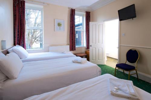 Habitación de hotel con 2 camas y TV en The Bournemouth Maemar Hotel, en Bournemouth