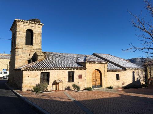 an old stone church with a clock tower on a street at El Bulín de Piñuecar in Piñuécar