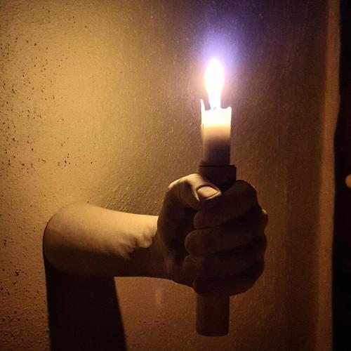 a hand holding a lit candle in the dark at Graceland Eco Retreat in Magoebaskloof